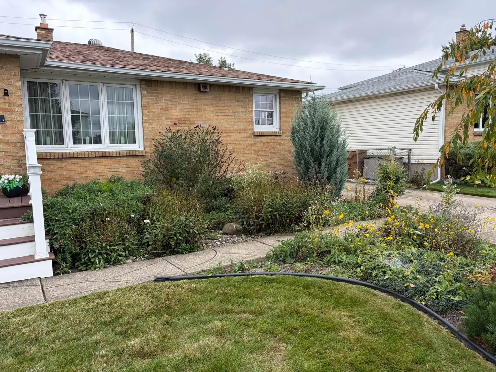 Front garden bed with shrubs and curved edging at a brick home, a Stone Mountain Lawn Care job