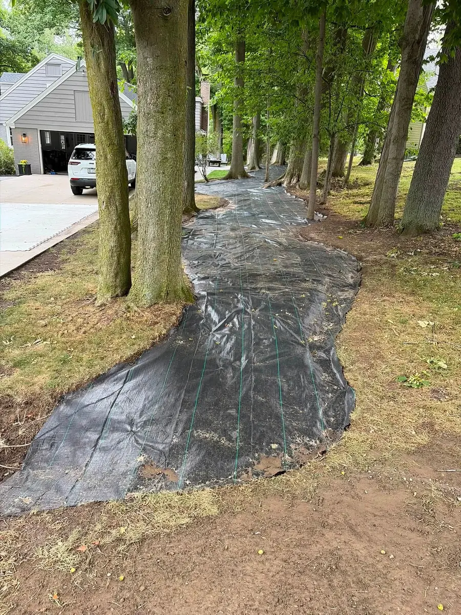 Landscape fabric laid across a wooded yard before bed work, a Stone Mountain Lawn Care job