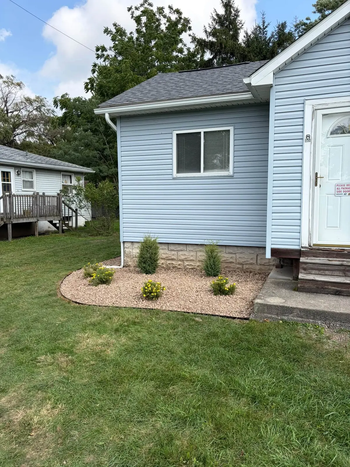 Trimmed lawn and a small mulch bed with plantings at a blue house, a Stone Mountain Lawn Care job